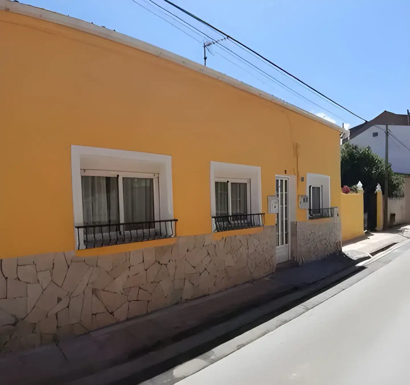 Los Pintores Segovia Fachada de casa tradicional pintada en color amarillo con zócalo de piedra